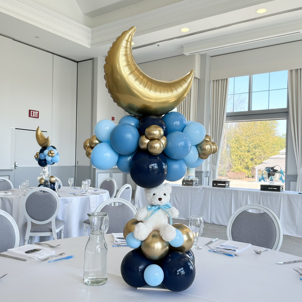 Decorative balloon arrangement with a gold moon and teddy bear on a glass door.